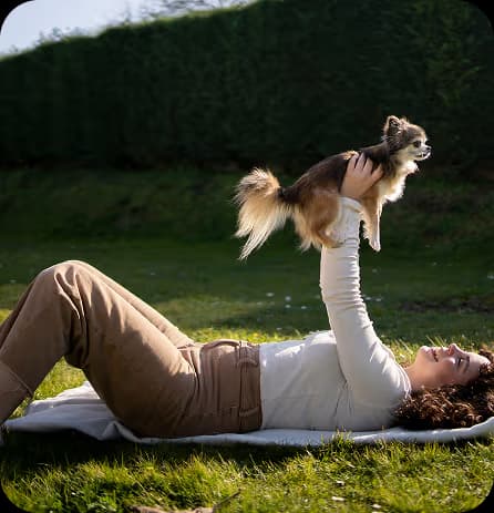 Person holding small dog on grass